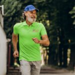 Homme qui marche, fais de la randonnée avec un polo vert brodé Les pieds Trithois, un vêtement professionnel été