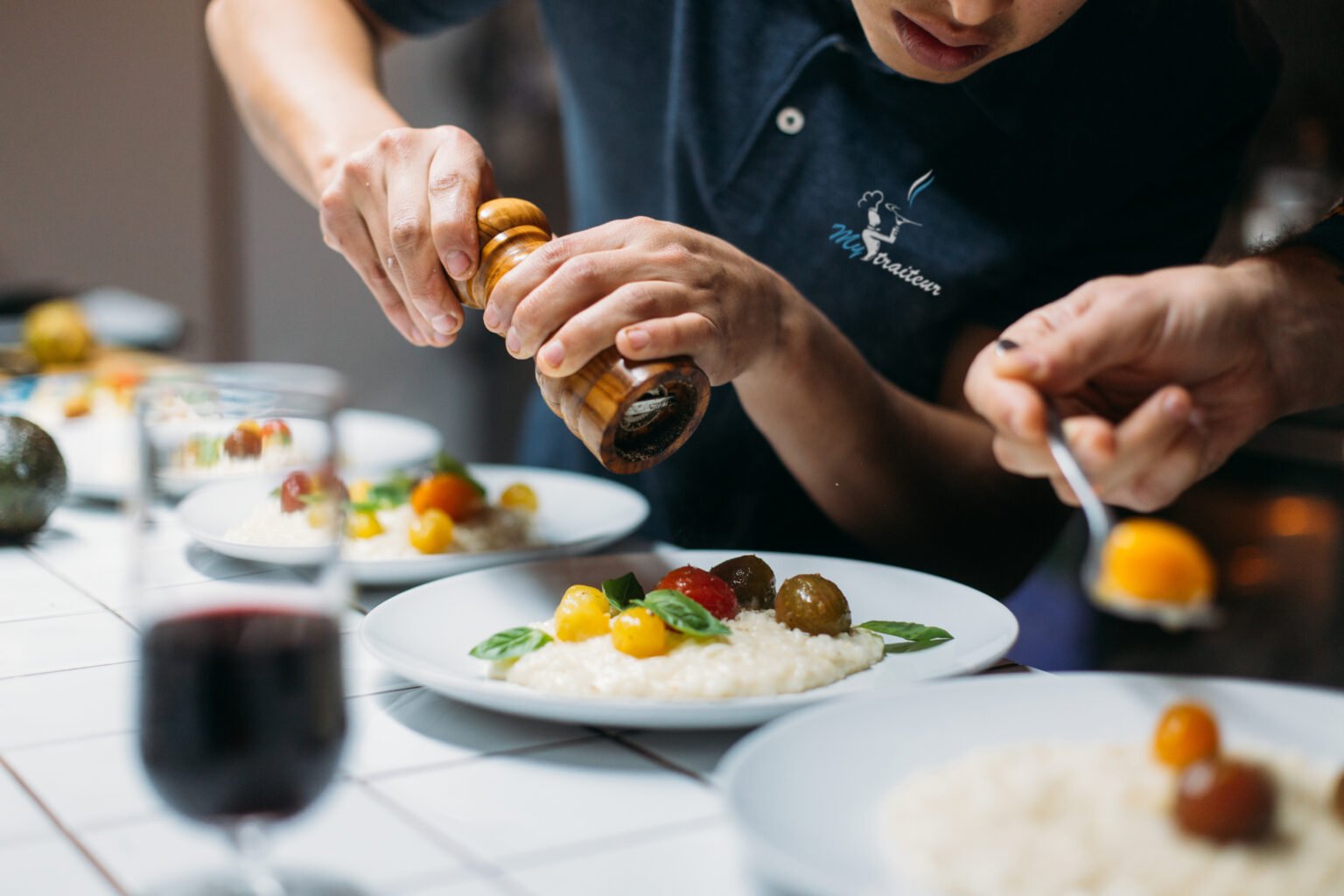 Chef cuisinier My Traiteur fait cuire des pates en polo noir brodé personnalisé